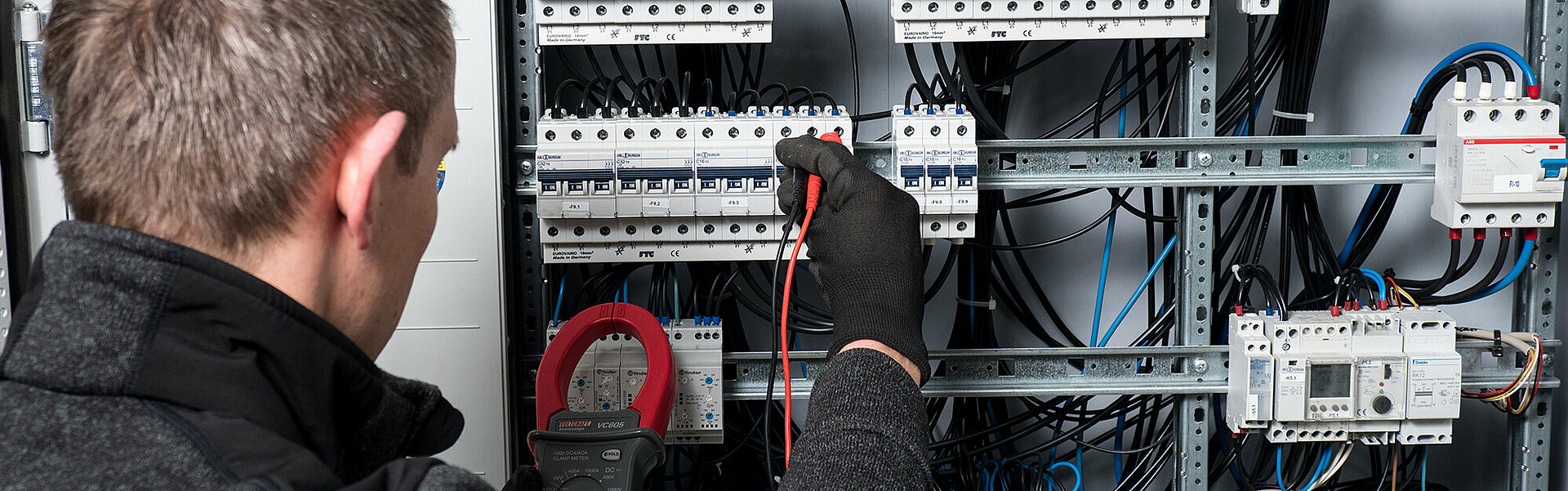 Mitarbeiter prüft Stromkabel in einem Schaltschrank